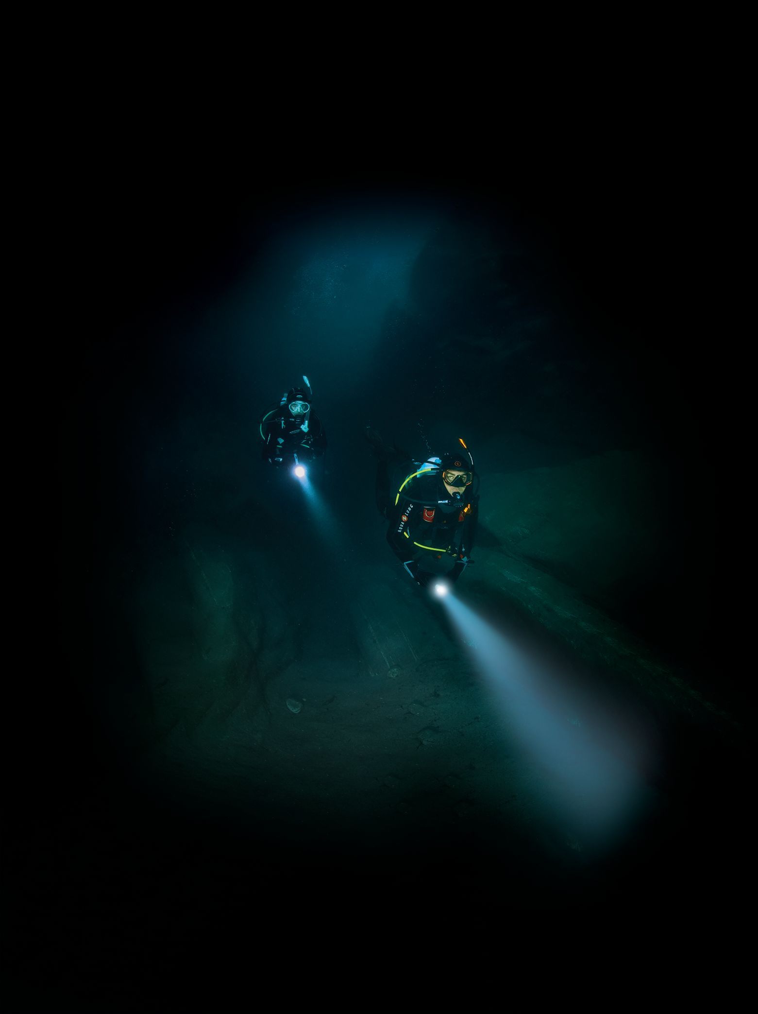 Deux plongeurs avec lampes torches dans les eaux profondes et sombres
